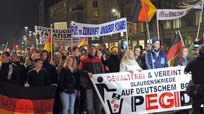 Demonstranten mit Pegida-Banner laufen auf die Kamera zu.