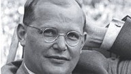 Schwarzweiß-Porträt von Dietrich Bonhoeffer mit Nickelbrille aus dem Jahr 1939.