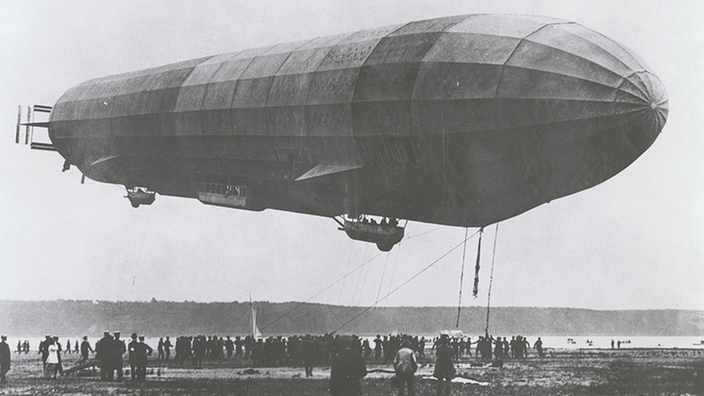 Ein Zeppelin fliegt über einer Stadt.