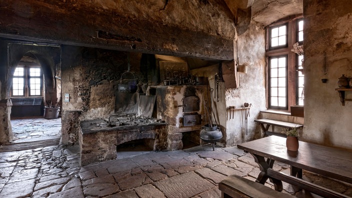 Küche mit Kamin, Kochstelle und rußgeschwärzter Decke in einer Ritterburg aus dem Mittelalter (Burg Ronneburg)