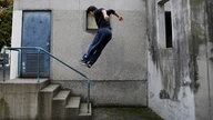 Parkour-Sportler springt über Geländer