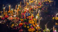 Blumen und brennende Kerzen treiben auf Wasser