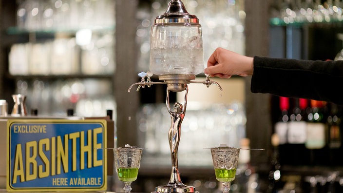 Absinth-Fontaine mit Gläsern und Schild