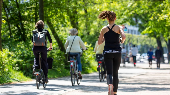 Eine Joggerin und Fahrradfahrer auf einem Weg.