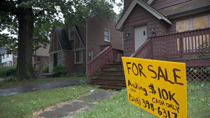 Haus mit "FOR SALE" Schild auf dem Rasen.