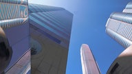 Blick von unten auf drei in die Höhe ragende Wolkenkratzer vor strahlend blauem Himmel