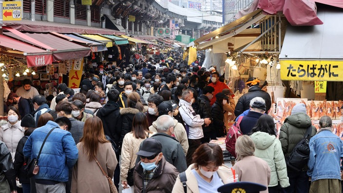 Eine Einkaufsstraße in Tokio, in der sich zahlreiche Menschen dicht an dicht drängen