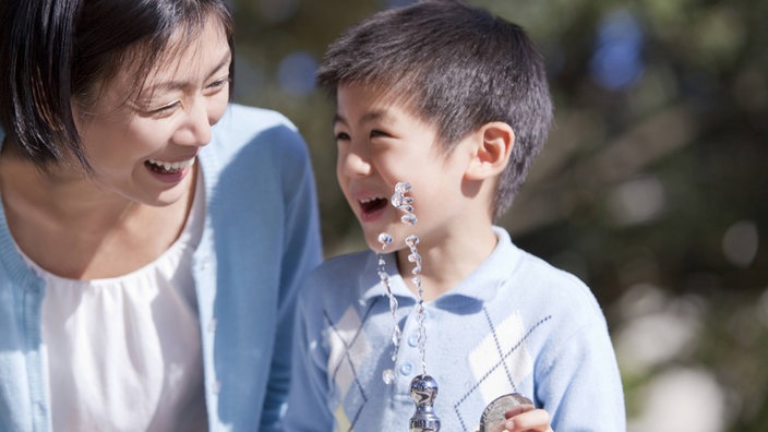 Eine japanische Mutter mit ihrem Sohn an einem Springbrunnen