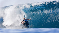 In einer großen Welle ist ein Surfer zu sehen.