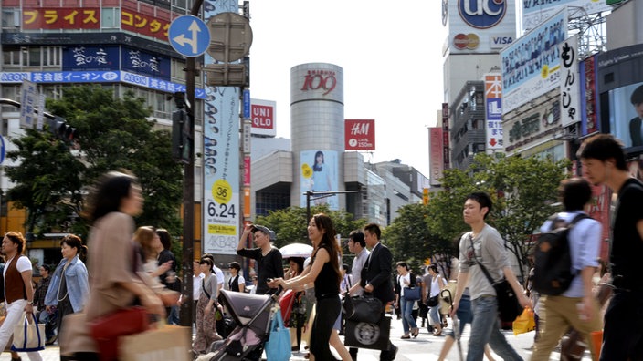 Fußgänger gehen im Stadtteil Shibuya über die Straße.