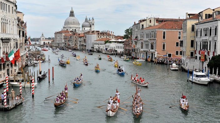 Das Foto zeigt mehrere geschmückte und bunt bemalte Gondeln auf dem Canal Grande