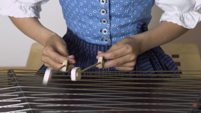 Eine Frau im Dirndlkleid spielt auf dem Hackbrett