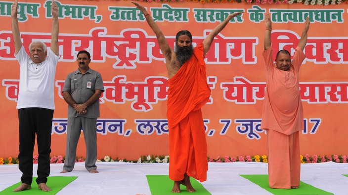 Yoga-Guru Ramdev und drei andere Männer bei Yogaübungen