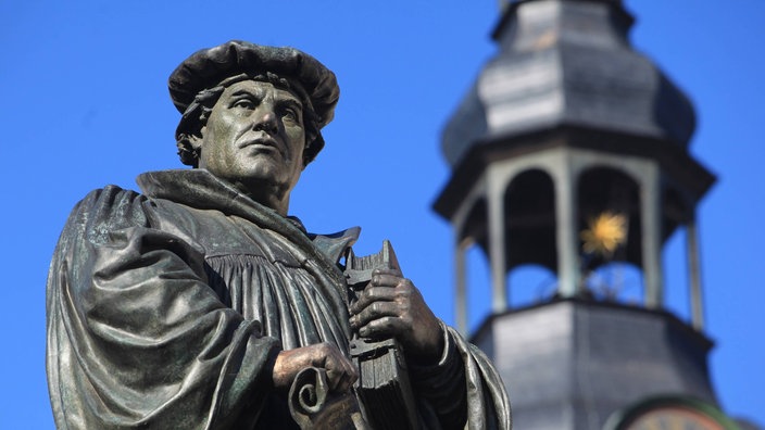 Denkmal des Reformators Martin Luther auf dem Marktplatz mit dem Turm der St. Andreaskirche im Hintergrund