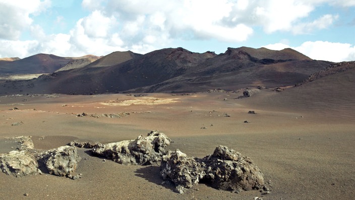 Lavalandschaft auf Lanzarote mit einem Vulkan im Hintergrund