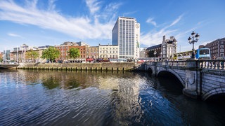 Eine Brücke über dem Fluss Liffey, im Hintergrund Häuser der Stadt Dublin