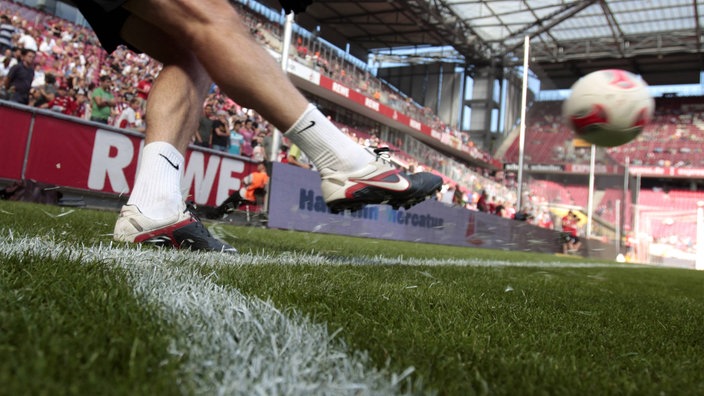 Die Unterschenkel eines Fußballers, der gerade einen Eckball tritt