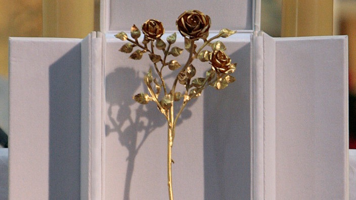 Ein kleiner Rosenstrauß aus vergoldetem Silber steht auf einem Altar