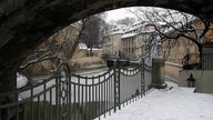 Ein kleiner Fluss im Winter, rechts und links des Flusses stehen Häuser.