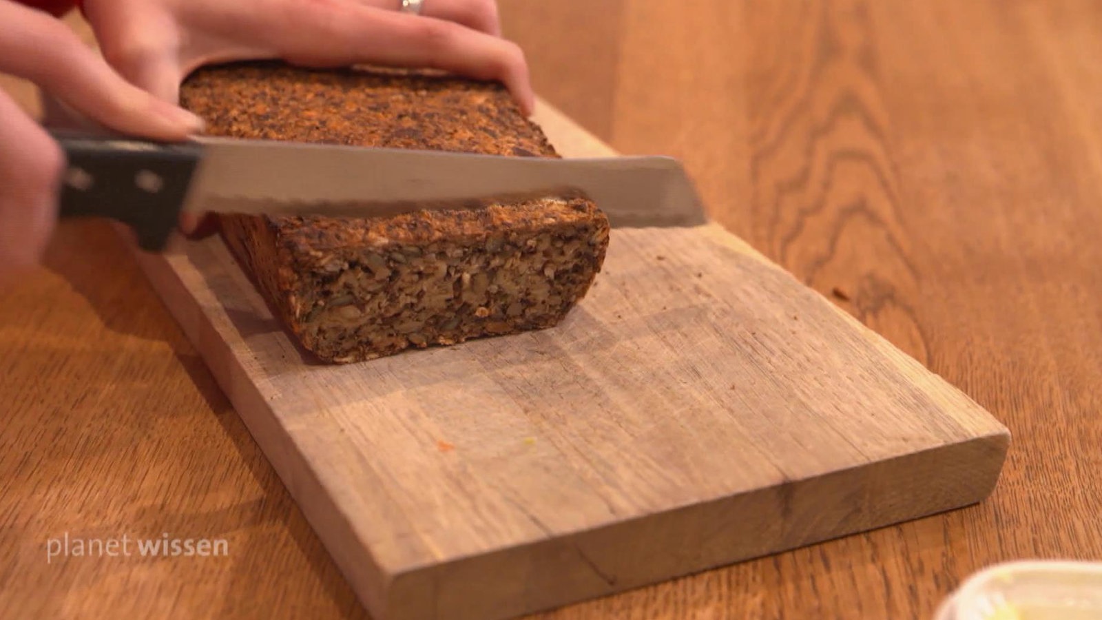 Von einem glutenfreien Brot wird mit dem Messer eine Scheibe geschnitten.