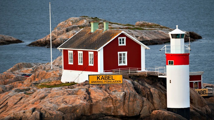 Schwedosches Holzhaus neben einem Leuchtturm