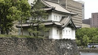 Das Foto zeigt einen Wachturm an der Außenmauer des Palastes, im Hintergrund als Kontrast das moderne Tokio.